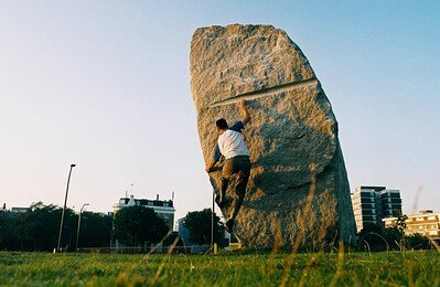A man climbing a boulder in an urban park