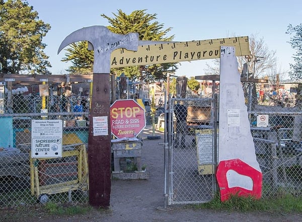 A fenced in area with a stop sign and a sign that says adventure playground