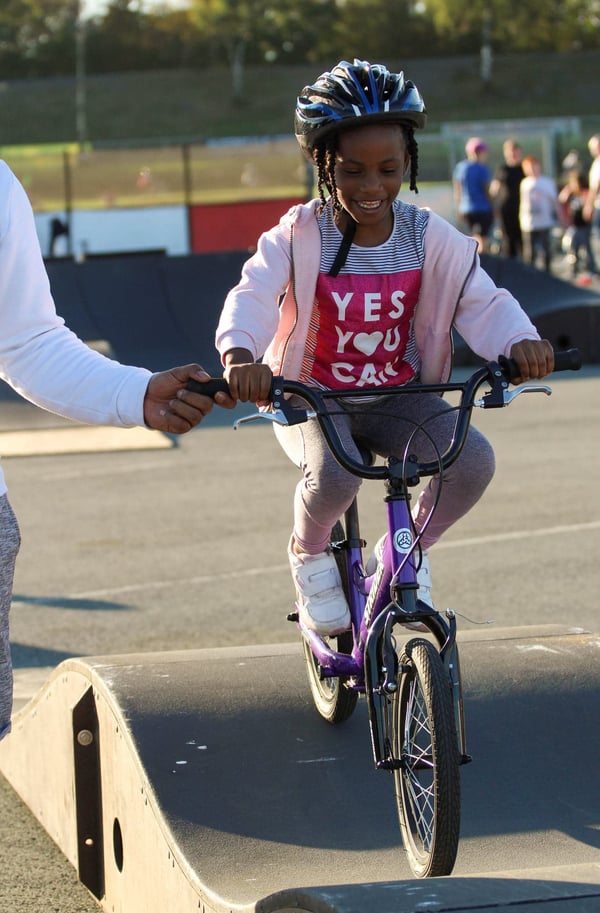 A primary school-aged girl rides a modular pumptrack. Adding a pumptrack to a community boosts the local cycling economy
