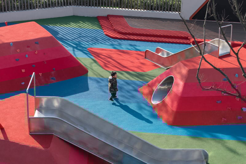 A child plays in Pomegranate Place playground, a multigenerational playground where adults and children meet, relax and socialize.