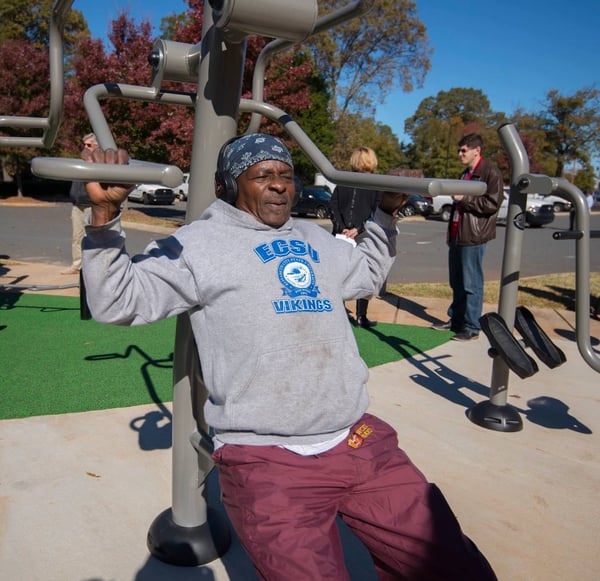 A patron makes use of the outdoor fitness equipment at Marion Diehl multigenerational playground in Charlotte, NC.