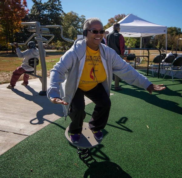 A patron smiles while balancing on a feature at Marion Diehl multigenerational playground in Charlotte, NC.