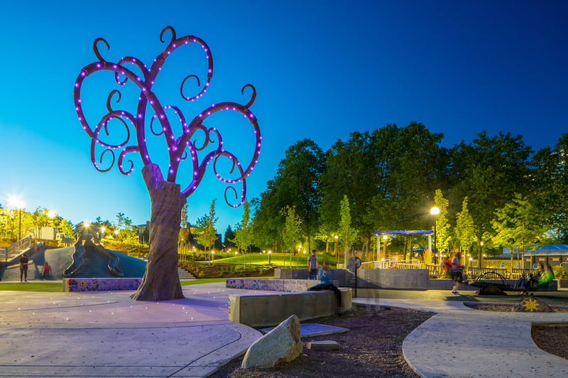 A whimsical looking tree lights up at night at Inspiration Playground, providing sensory delight. The playground is universally accessible and located in Bellevue, WA, USA.