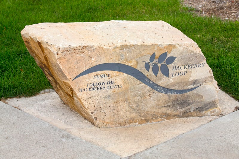 An artistic marker etched in natural stone along an accessible path at Discovery Park’s multigenerational playground.