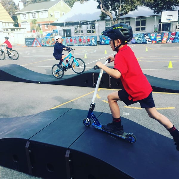 Children ride a modular pumptrack outside a primary school in New Zealand