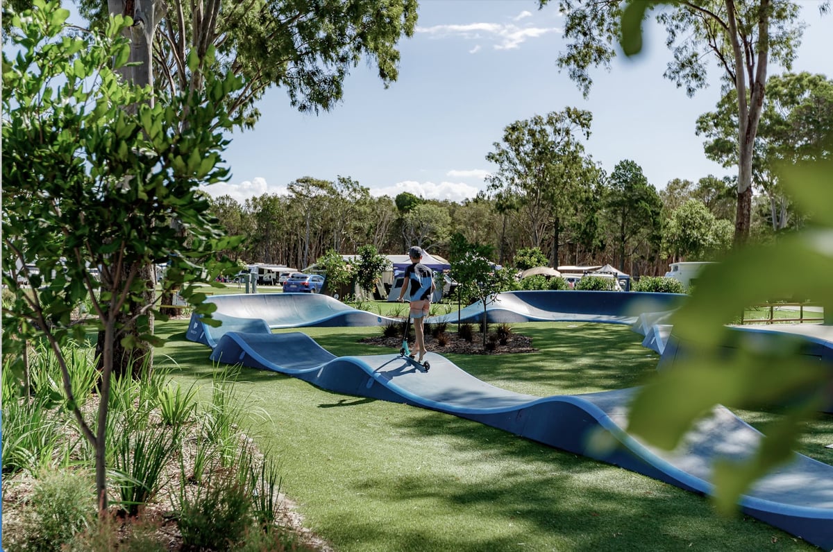 How to ride a pumptrack - boy rides a scooter on a pumptrack at a Big 4 Holiday Park in Australia