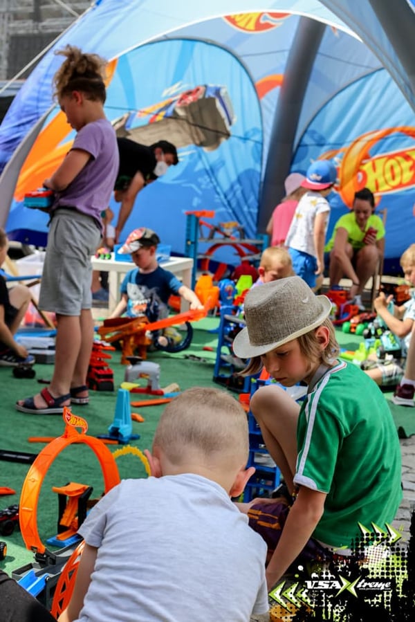 Kids play with Hot Wheels modular track systems at a public event featuring a Hot wheel branded pumptrack