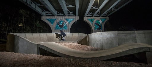 Person riding a PARKITECT modular pumptrack under an overpass