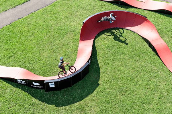 Pumptracks are a great intro to mountain biking - two kids ride a PARKITECT modular pumptrack