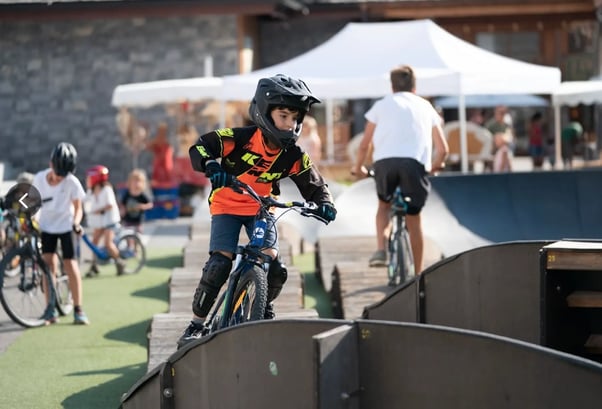 Boy in helmet fiercely competes on outdoor pumptrack.